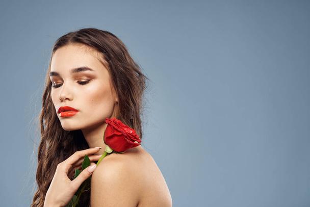 mujer con una rosa en sus manos hombros desnudos maquillaje de noche labios rojos - Foto, Imagen