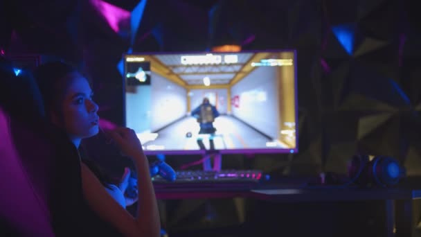 Νεαρή γυναίκα παίζει ένα online παιχνίδι στο gaming club - τραβώντας μια τσίχλα από το στόμα της - Πλάνα, βίντεο