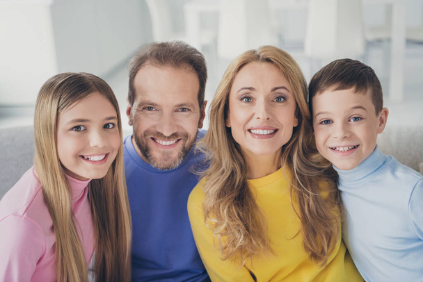 Photo of idyllic family mom dad and two children boy girl look in camera toothy smile sit couch in house indoors - Photo, image