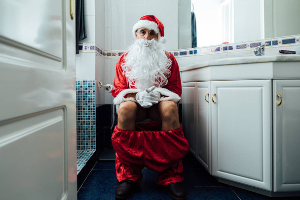 Санта Клаус сидит в унитазе и какает. - Фото, изображение