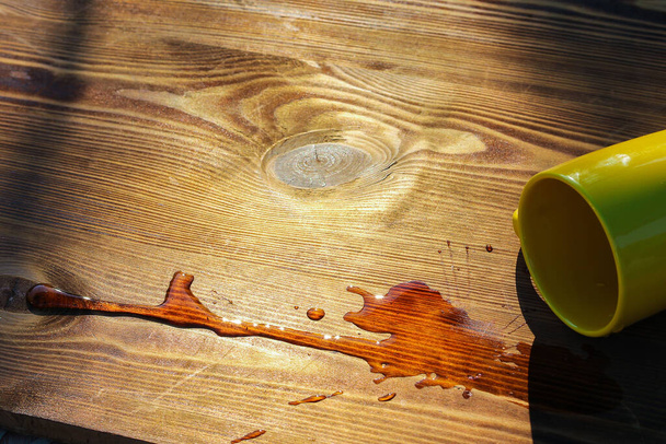 Gemorste drank op tafel. Een omgekeerde mok thee op een houten tafel - Foto, afbeelding