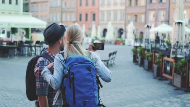 Zadní pohled na muže a ženu, jak dělají selfie na smartphonu v centru města - Záběry, video