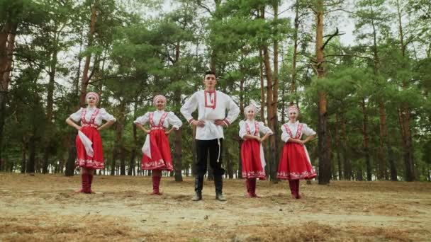 Jeden muž a čtyři mladé ženy tančí ruské tradiční tance v letním lese - Záběry, video