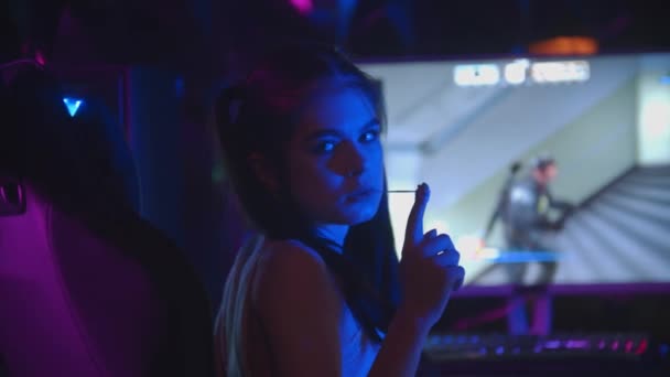 Молодая привлекательная женщина в игорном клубе вытаскивает жвачку изо рта - глядя в камеру - Кадры, видео