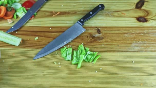 İnsan ellerine tepeden bakıldığında dilimlenmiş yeşil biber ve bıçaklarla ahşap masa düzenlenir. - Video, Çekim