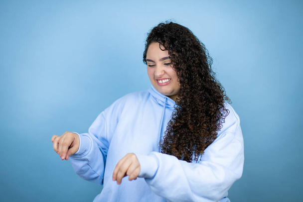 Young beautiful woman wearing casual sweatshirt over isolated blue background disgusted expression, displeased and fearful doing disgust face because aversion reaction. Annoying concept - Photo, Image
