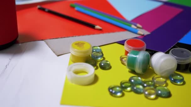 Στο τραπέζι είναι τυχαία τοποθετημένα Avocarel χρώματα, μολύβια, βούρτσες, έγχρωμο χαρτί - Πλάνα, βίντεο