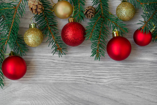 Noel kompozisyonu köknar dalları, köknar kozalakları ve kırmızı, ahşap tahtalardaki altın toplar - Fotoğraf, Görsel