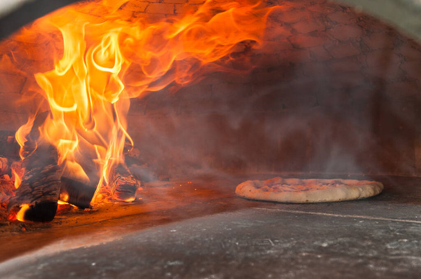Italian pizza that is cooking in a wood oven - Photo, Image
