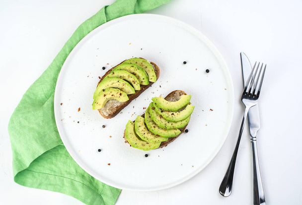 Culinary background with avocado sandwiches on a white background with Cutlery and napkin. - Foto, afbeelding