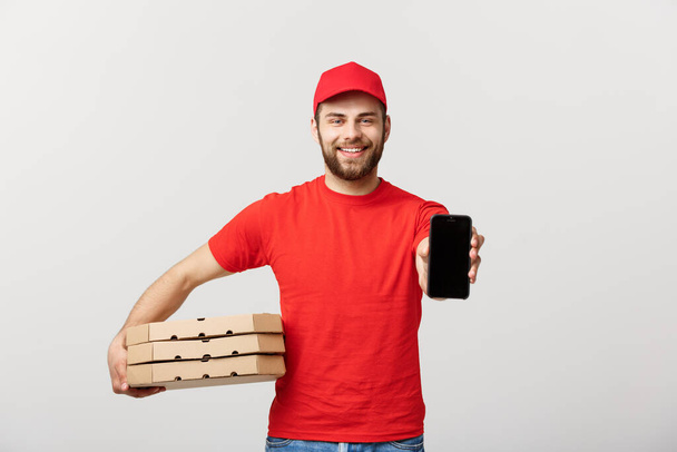 Πίτσα delivery man κρατώντας ένα κινητό και κουτιά πίτσα πάνω από λευκό φόντο. - Φωτογραφία, εικόνα