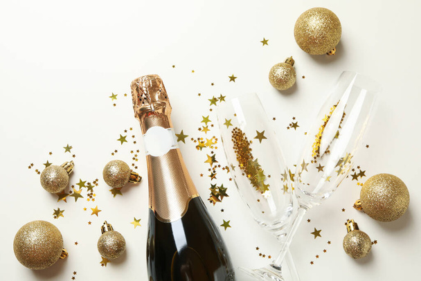 Champagne en glitter op witte achtergrond, bovenaanzicht - Foto, afbeelding