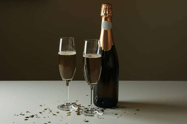 Пляшка та келихи з шампанським та блиском на білому столі
 - Фото, зображення
