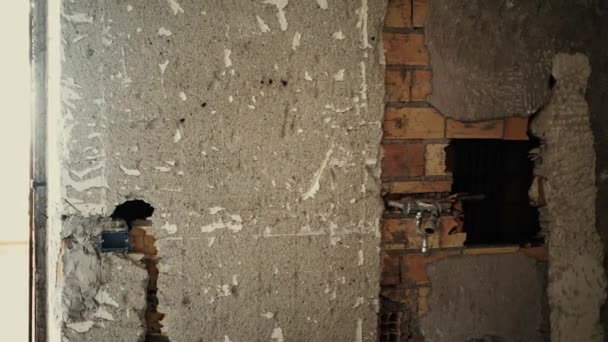 Eine kaputte Wand in der Wohnung. Ziegelwand mit Rohren - Filmmaterial, Video