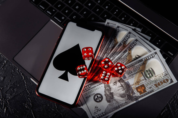 Dice, smartphone and dollar banknotes on keyboard. Online casino and gambling concept - Foto, Imagen