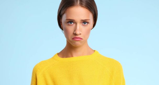 nuori emotionaalinen nainen keltainen villapaita on surullinen ja järkyttynyt sininen värillinen backgroun - Valokuva, kuva