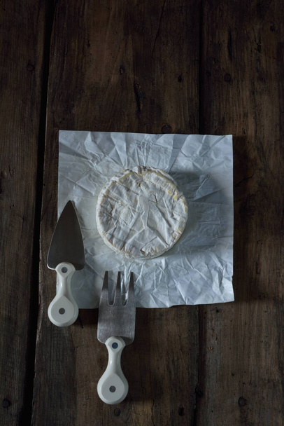 Camembert cheese with cheese fork and cheese knife  on wooden rustic table - Photo, Image