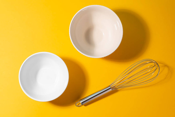 Top view on two different ceramic bowls and a metal whisk - 写真・画像