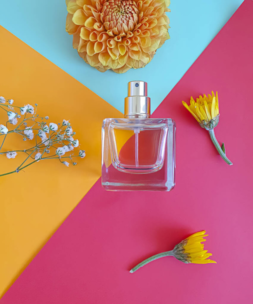 μπουκαλάκι άρωμα λουλούδι σε ένα χρωματιστό φόντο - Φωτογραφία, εικόνα
