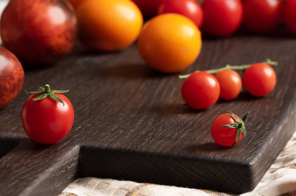Pomidor z sepalem i pedicelą. Pomidory wiśniowe na tle dużych pomidorów - Zdjęcie, obraz