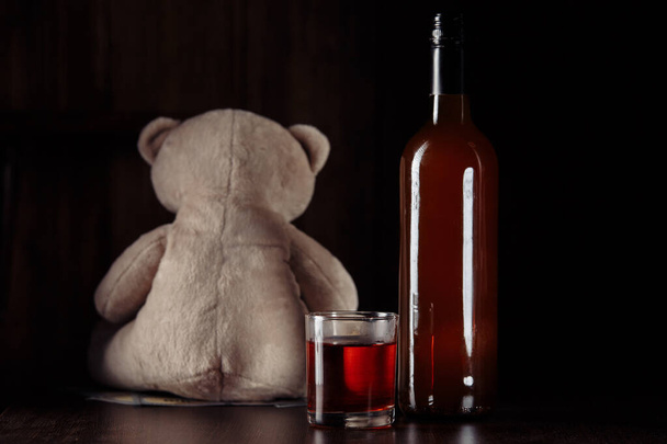 Алкоголь і насилля над дітьми. Тедді-ведмідь як символ дитячої безпеки і пляшки з склом. - Фото, зображення