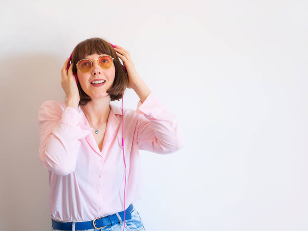 Junge glückliche Frau im rosa Hemd mit Kopfhörern - Foto, Bild