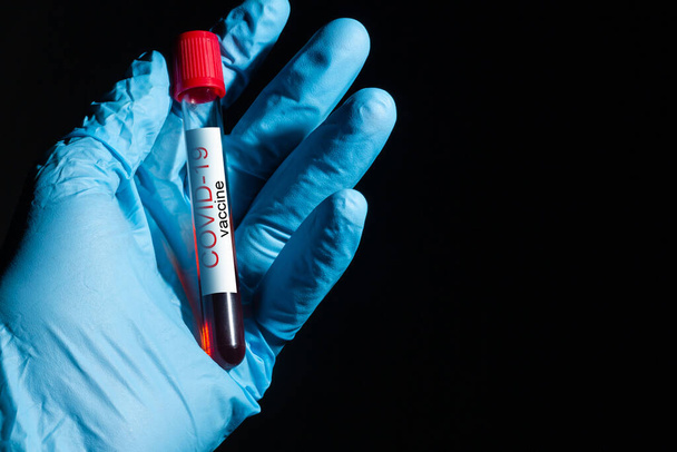 Hand in Hand medizinischer Handschuh hält Coronavirus Covid-19 Impfflasche, Nahaufnahme Detail - Foto, Bild