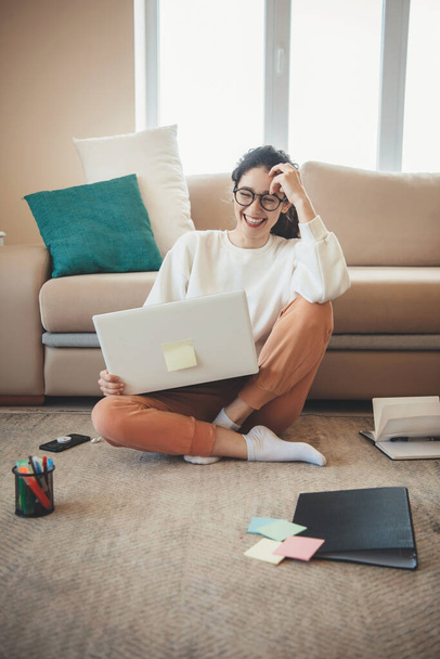 Uśmiechnięta biała kobieta bierze lekcje online z laptopem na podłodze w salonie - Zdjęcie, obraz