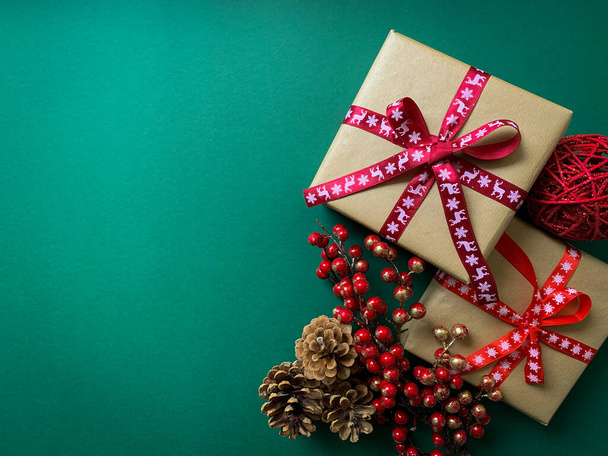 Christmas bright green background with gift boxes and branches of berries and pine cones. Warm Christmas composition with copy space. - Photo, Image
