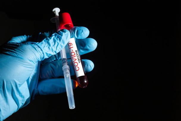 El médico sostiene la vacuna COVID 19 Coronavirus en su mano, muestra de sangre infectada en el tubo de muestra, vacuna e inyección de jeringa. Se utiliza para la prevención, inmunización y tratamiento de COVID-19. - Foto, Imagen