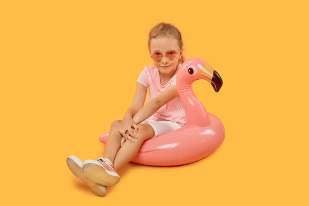 Menina com um círculo de natação rosa na forma de um Flamingo em óculos de sol. - Foto, Imagem
