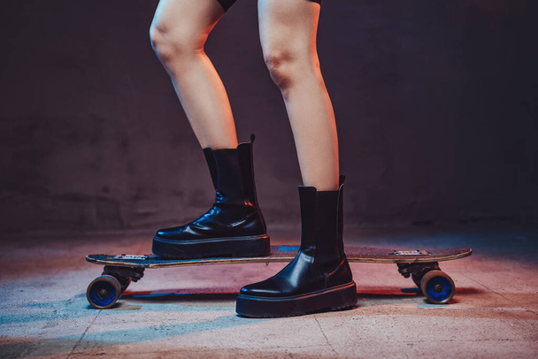 Womans legs on skateboard in dark background with lights - Photo, Image