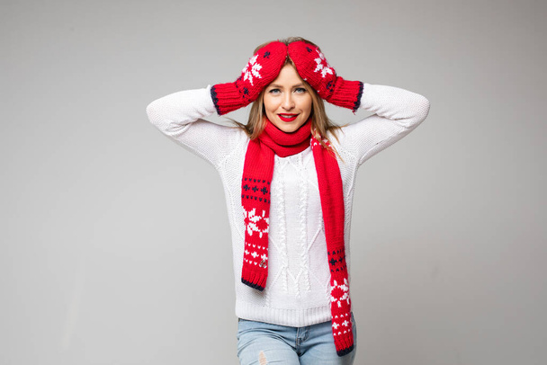 attraktive Frau in weißem Pullover, rotem Schal und roten Handschuhen mit weihnachtlichem Design - Foto, Bild