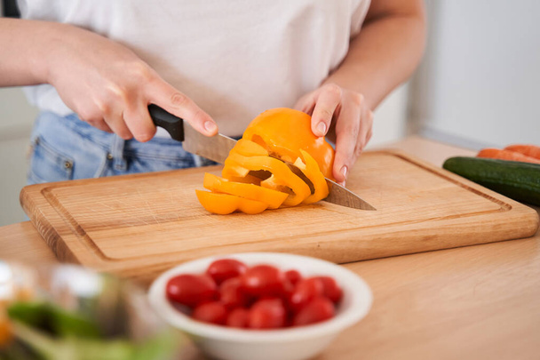 Woman chopping orange pepper - Foto, immagini