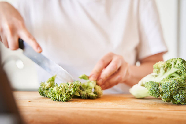 Woman chopping broccoli with a knife - Fotoğraf, Görsel