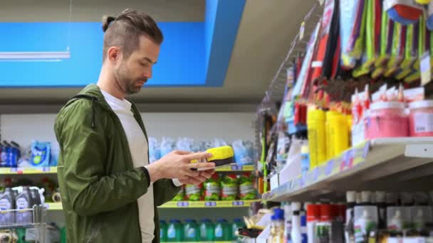 Joven macho está comprando una esponja de coche en tienda especial - Metraje, vídeo