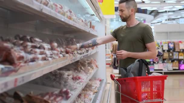 homem está escolhendo salsicha no supermercado, lendo ingredientes - Filmagem, Vídeo