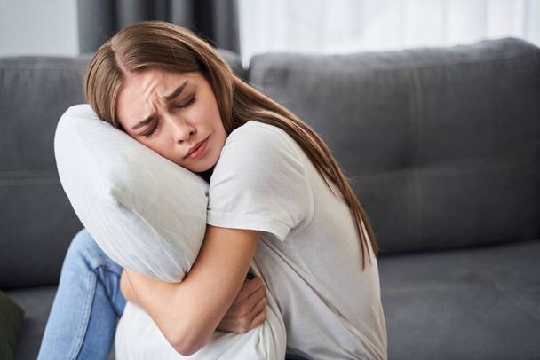 Depresyonlu bir kadın yastığa sarılıyor. - Fotoğraf, Görsel