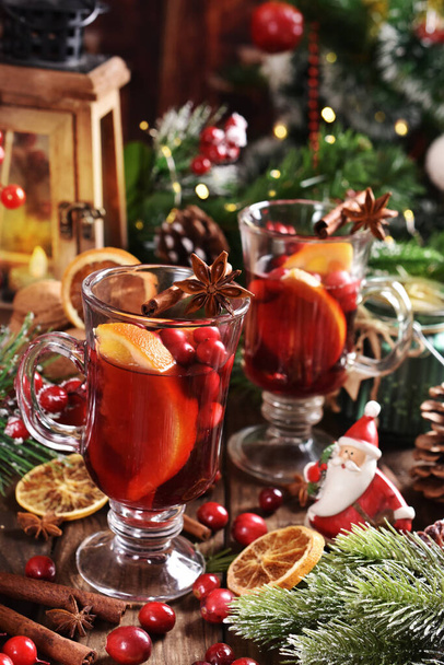 two glasses of mulled wine with orange, cranberries and spices on wooden table for Christmas - Fotó, kép