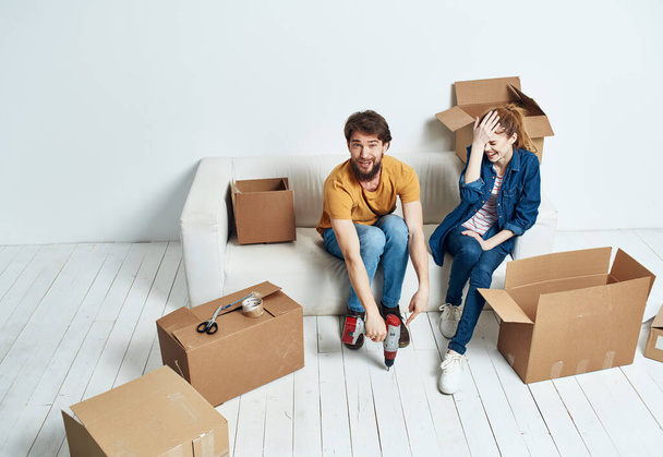 young couple on white couch with boxes of fun chatting - 写真・画像