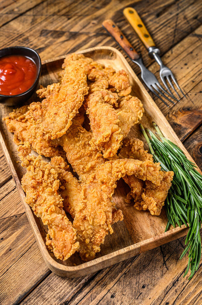 Breaded chicken breast tenders strips with ketchup. Wooden background. Top view. - Photo, image
