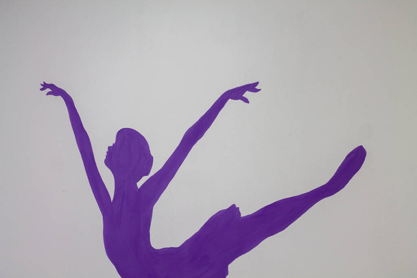 Uma silhueta de uma bailarina pintada na parede. Decorações de estúdio de balé. Bailarina roxa desenho. - Foto, Imagem