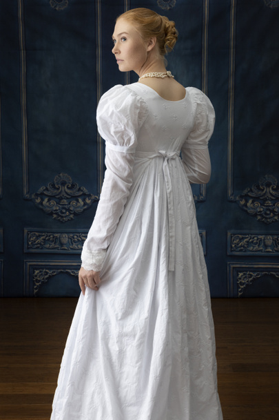 Eine Regency-Frau in einem weißen Musselinkleid steht in einem Raum - Foto, Bild