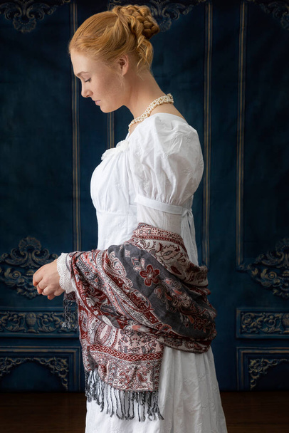 Una mujer de regencia con un vestido de muselina blanca de pie en una habitación - Foto, imagen