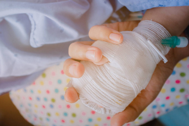 Close-up picture of an Asian mother holding a sick son's hand - Photo, Image