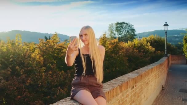 Pretty girl making selfie on smartphone in front of beautiful nature landscape - Footage, Video
