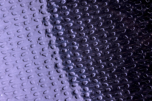 Cloe encima de la superficie brillante iluminada de la cinta adhesiva negra con los divots - Foto, Imagen