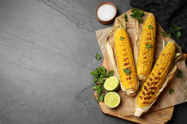 Tasty grilled corn on black table, flat lay. Space for text - Foto, Bild