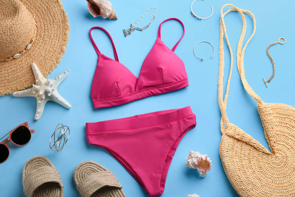 Beautiful pink bikini and beach accessories on light blue background, flat lay - Фото, изображение