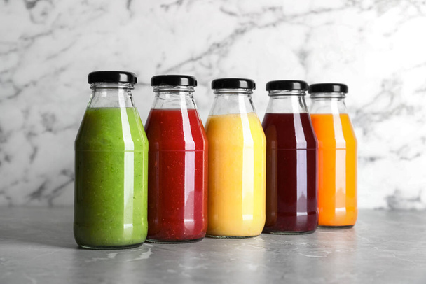 Bottles with delicious colorful juices on marble table - Foto, Bild